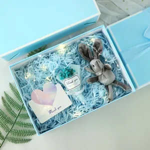 Blauwe geschenkdoos set met pluche konijn, gedroogde bloemen en lichtjes voor feestdagen.