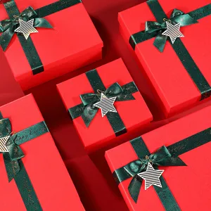 Red glitter Christmas gift boxes featuring dark green ribbons and star charms for holidays.