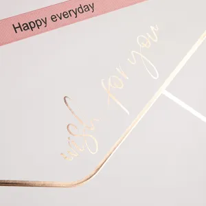 Roze geschenkdoos detailweergave met roze lint en elegante gouden gestempelde tekstdecoratie.