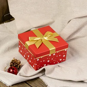 Detailed close-up shot of a red Christmas gift box featuring gold ribbon bow and stars on fabric.