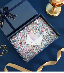 Luxury blue gift box detail view showcasing colorful foam balls and greeting card inside.