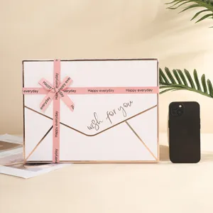 Envelop stijl witte geschenkdoos met roze lint en goudfolie tekst, ideaal voor cosmetica.
