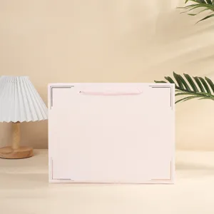 Roze papieren geschenkdoos detailweergave met lint handvat en elegante hoekdecoratie.