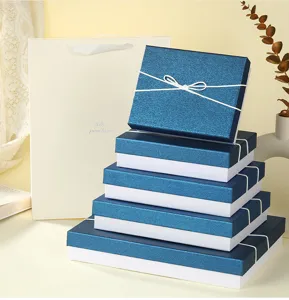 Detailed view of stacked blue gift boxes with white ribbon bow and paper bag scene display.