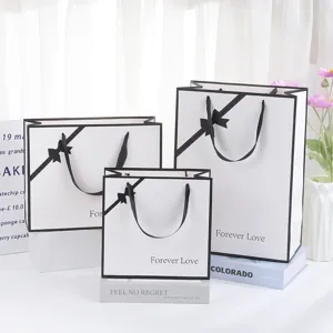 Elegant white gift bags with black borders and bows for cosmetics, holidays, and parties.