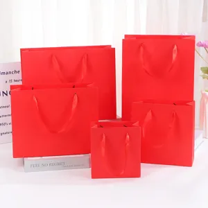 Red paper gift bags set with ribbon handles for festive packaging, cosmetics and retail use.