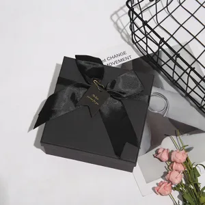 Dettaglio scatola regalo nera con nastro elegante e etichetta decorativa per le festivita.