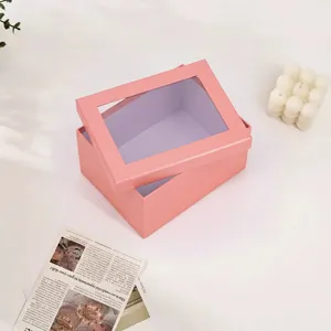 Caja de regalo de papel rosa con tapa de ventana transparente para cosméticos y velas.