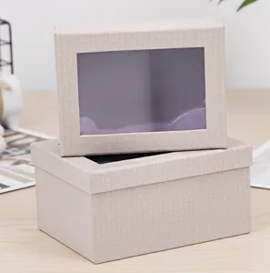 Vista detallada de caja de regalo de papel con ventana transparente y superficie texturizada.
