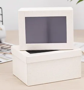 Detalle de caja de regalo con ventana de tela beige, ideal para flores y cosméticos.