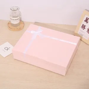 Pink gift box with white ribbon for holiday packaging, elegant and stylish presentation box.