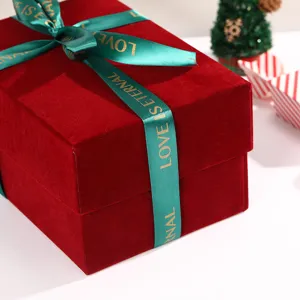 Close-up of burgundy velvet gift box with green ribbon bow and printed love text details.