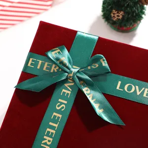 Burgundy velvet gift box detail, green ribbon bow with love text for holiday packaging.