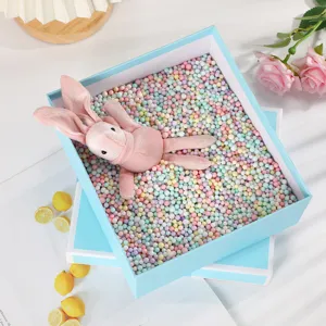 Blue gift box detail view featuring colorful foam filling, pink plush rabbit and decorative roses.