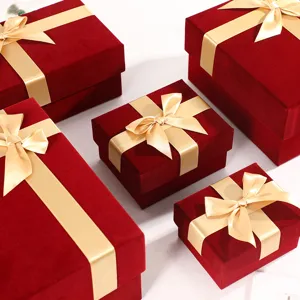 Red velvet gift box with gold bow, luxury packaging box for Christmas gifts, detail view.