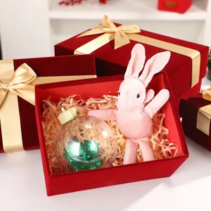 Detail shot of luxury red velvet gift box with gold ribbon, filled with shred paper and plush toy.
