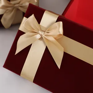 Velvet gift box detail showing the elegant golden ribbon bow and soft red texture surface.