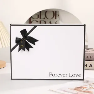 White gift box with black ribbon and bow detail, elegant packaging for Valentine day present.