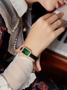 Nahaufnahme einer eleganten quadratischen grünen Quarzuhr am Handgelenk mit Ring.