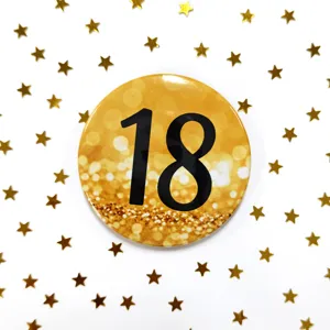 Dettaglio spilla 18esimo compleanno oro, bottone metallico rotondo con numero nero.