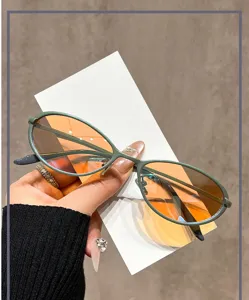 Close-up shot of trendy metal oval cat-eye sunglasses with gradient orange anti-UV lenses.