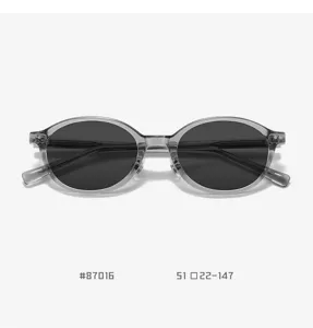 Detail view of trendy TR90 oval sunglasses featuring clear grey frames and dark lenses.