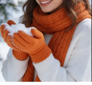 Gros plan détaillé montrant une écharpe en tricot orange et des gants chauds dans la neige.