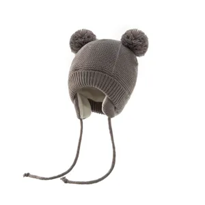 Graue gestrickte Kindermütze mit süßen Doppelbommeln und warmen Ohrenklappen für Winter