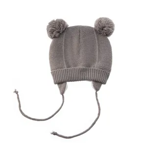 Warme graue Kinder Strickmuetze mit niedlichen Bommeln Ohrenklappen und langen Baendern.