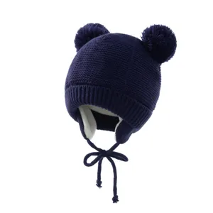 Nahaufnahme der dunkelblauen Kinder Strickmütze mit süßen Pompons und warmen Ohrenklappen.