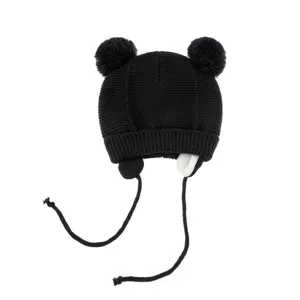 Detailansicht der schwarzen Kinder Strickmütze mit flauschigen Bommeln und Ohrenklappen.