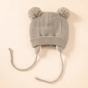 Detailansicht der kuscheligen Kinder Strickmütze mit süßen Bommeln und warmen Ohrenklappen.