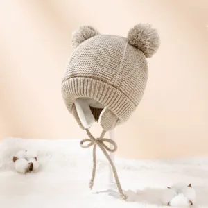 Detailansicht der süßen Baby Strickmütze mit zwei Bommeln und Ohrenklappen, weiche Wintermütze.