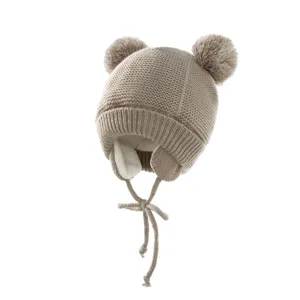 Detailaufnahme der Kinder Strickmütze mit zwei Pompons, Ohrenklappen und warmem Futter.