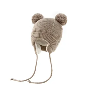 Detailansicht der niedlichen beige Strick-Babymütze mit warmem Futter und zwei Bommeln.