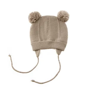 Beige Kinder Strickmütze Detail, süße Doppel-Pompon Baby Haube mit warmen Ohrenklappen.