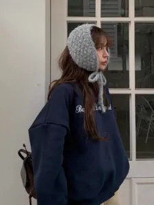Gemütliche graue Strickmütze mit Bändern, winterliche Ohrenklappen Kapuze Detail.