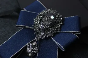 Close-up detail of dark blue rhinestone bow tie with sparkling crystals and pendant ribbon.
