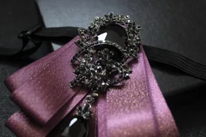 Men's purple ribbon bow tie with black crystal rhinestone brooch detail for formal suit apparel.