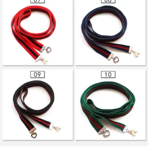 Decorative fabric neck ribbon choker with metal charms and striped webbing design.