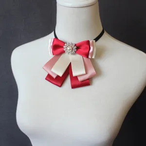 Detailed close-up of multi-layer ribbon bow tie featuring red, pink, and white satin fabric.