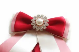 Detailed closeup view of multi-layer ribbon bow tie with rhinestone pearl center brooch.