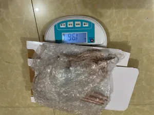 Detail view of metal wind chime tubes securely packed in bubble wrap on a digital scale.