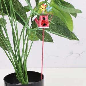 Detailed close up of a cute metal watering can garden stake with ladybug and flowers.
