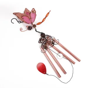 Dettaglio del carillon a vento a forma di libellula rosa con tubi in rame e acrilico.