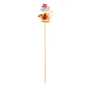 Close-up detail of the metal garden stake featuring a yellow watering can and colorful flowers.