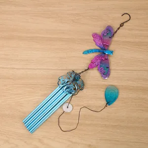 Metal dragonfly wind chime detail showing colorful painted glass and blue metal hanging tubes.