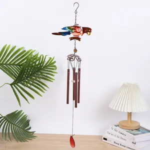 Détail de carillon à vent perroquet en métal avec oiseau coloré et tubes suspendus pour décoration.