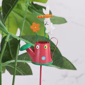 Metal garden flower stake detail shot, cute watering can design with flowers and dragonfly.