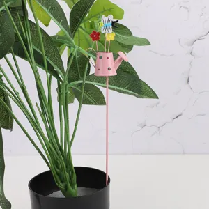 Metal garden stake detail, pink watering can with flowers and bee for potted plants decor.